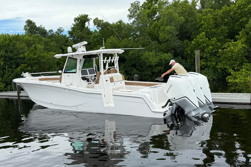 Slide: The Image of 2020 Caymas 341 CC boat docked with triple Mercury engines, surrounded by lush greenery. - 14