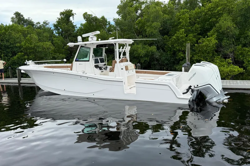 Slide: The Image of 2020 Caymas 341 CC boat docked on calm water with lush greenery background. - 15