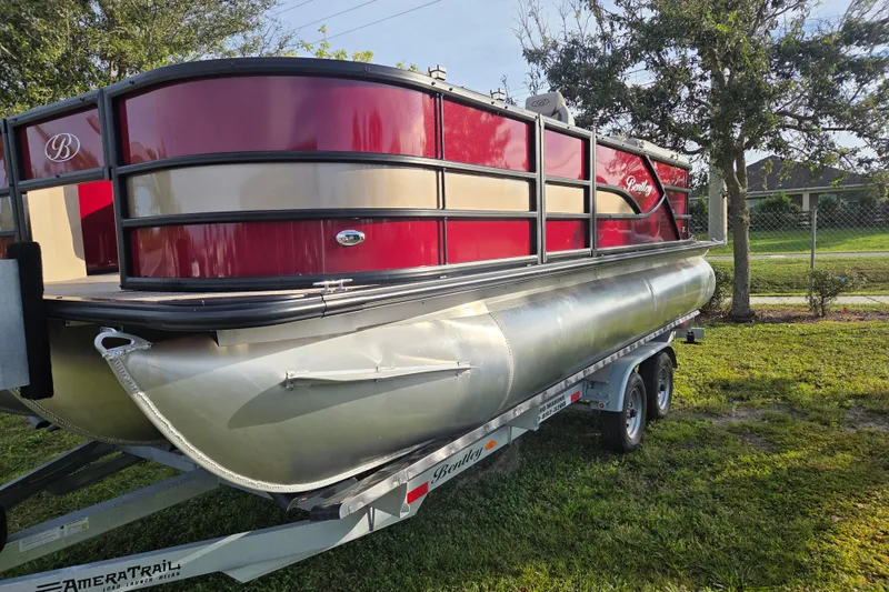 Slide: The Image of 2026 Bentley Pontoons Fish 203 on trailer, red and silver design, parked on grass. - 10