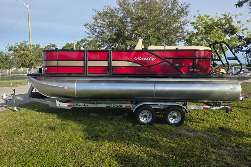 Slide: The Image of 2026 Bentley Pontoons Fish 203 on trailer, red and beige design, parked on grass. - 11
