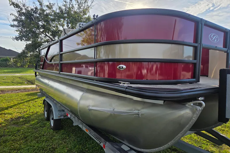 Slide: The Image of 2026 Bentley Pontoons Fish 203 on trailer, red and silver design, parked on grass. - 9