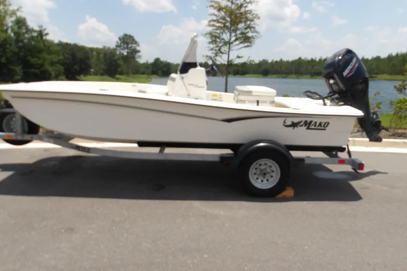 The Image of 2026 Mako Pro Skiff 15 CC boat on trailer by a lake. - 1