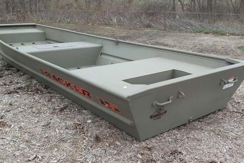 Slide: The Image of 2026 Tracker Grizzly 15 Jon boat on dry ground, showcasing its sturdy design. - 2