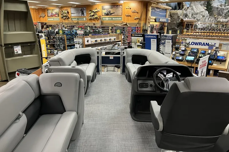 Slide: The Image of 2026 Sun Tracker SportFish 22 DLX interior in a showroom, featuring gray seating and a steering console. - 3