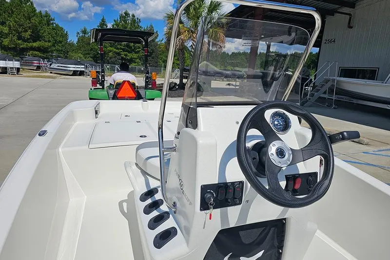 Slide: The Image of 2026 Mako Pro Skiff 15 CC boat interior with steering wheel and console, parked outdoors. - 11