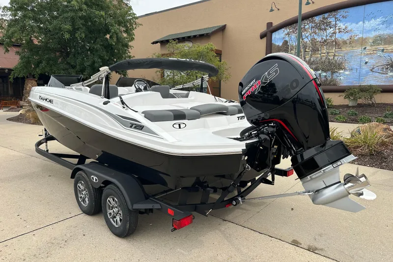 Slide: The Image of 2026 Tahoe T21 boat with Mercury engine on trailer, parked outdoors. - 2