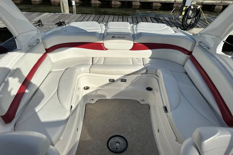 Slide: The Image of 2008 Larson LXi 288 boat interior with white and red seating, docked at a marina. - 11