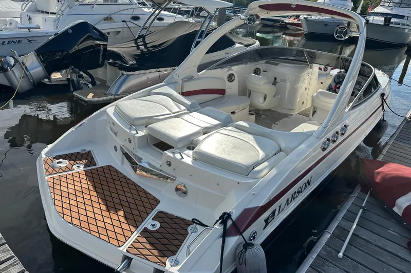 Slide: The Image of 2008 Larson LXi 288 boat docked, featuring white seating and sleek design. - 2