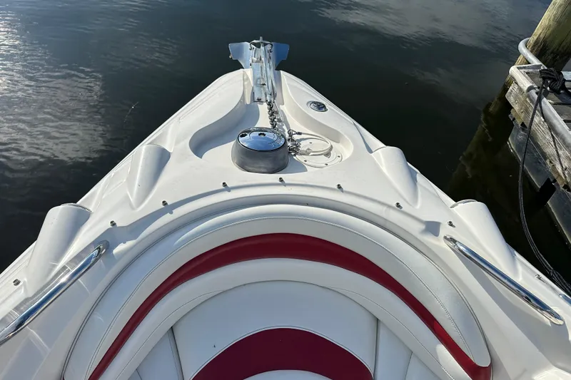 Slide: The Image of 2008 Larson LXi 288 boat bow with white and red seating, docked on calm water. - 21