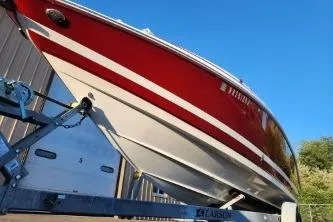 Slide: The Image of 2008 Larson LXi 288 boat on trailer, red and white design, clear blue sky. - 31