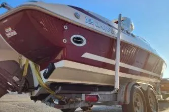 Slide: The Image of 2008 Larson LXi 288 boat on trailer, red and white hull, sunny day. - 32