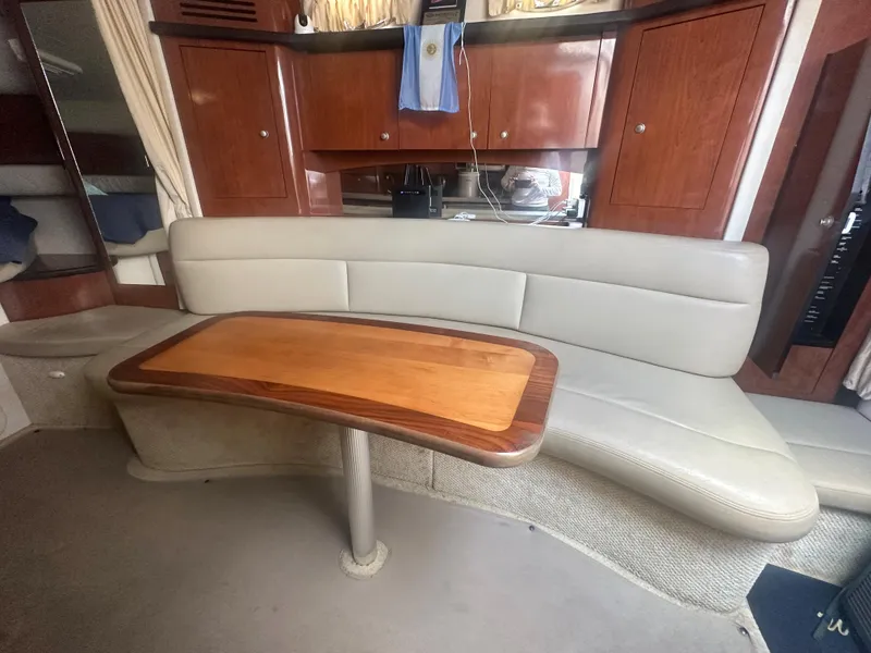 Slide: The Image of Interior of a 2006 Sea Ray 340 Sundancer with a curved sofa and wooden table. - 48
