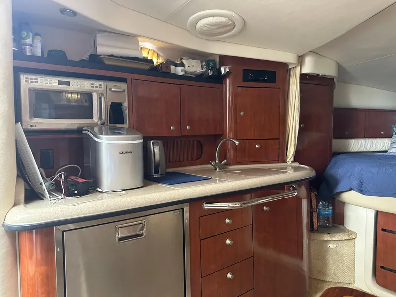 Slide: The Image of 2006 Sea Ray 340 Sundancer interior kitchen with microwave, sink, and wooden cabinets. - 52