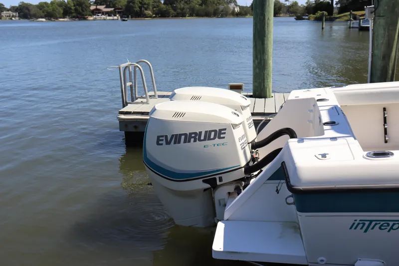 Slide: The Image of 1997 Intrepid 322 boat with Evinrude engines docked by a serene lake. - 4