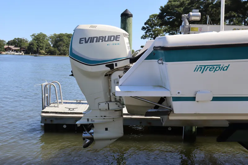 Slide: The Image of 1997 Intrepid 322 boat with Evinrude E-TEC outboard motor docked by the water. - 5