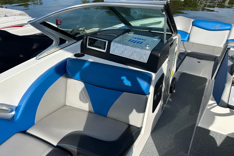 Slide: The Image of 2016 MasterCraft X23 boat interior with blue and gray seating, near water. - 11