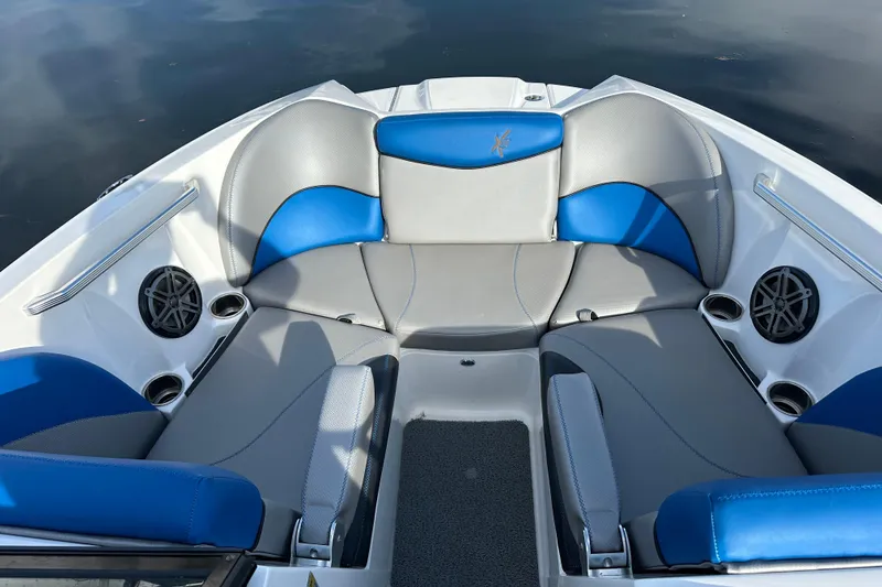 Slide: The Image of 2016 MasterCraft X23 boat interior with blue and gray seating, cup holders, and speakers. - 18
