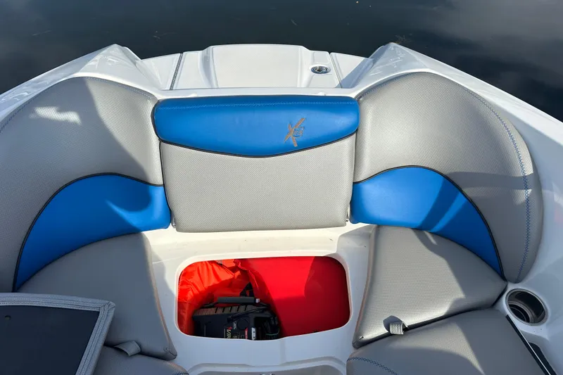 Slide: The Image of 2016 MasterCraft X23 boat interior with blue and gray seating, storage compartment open. - 19