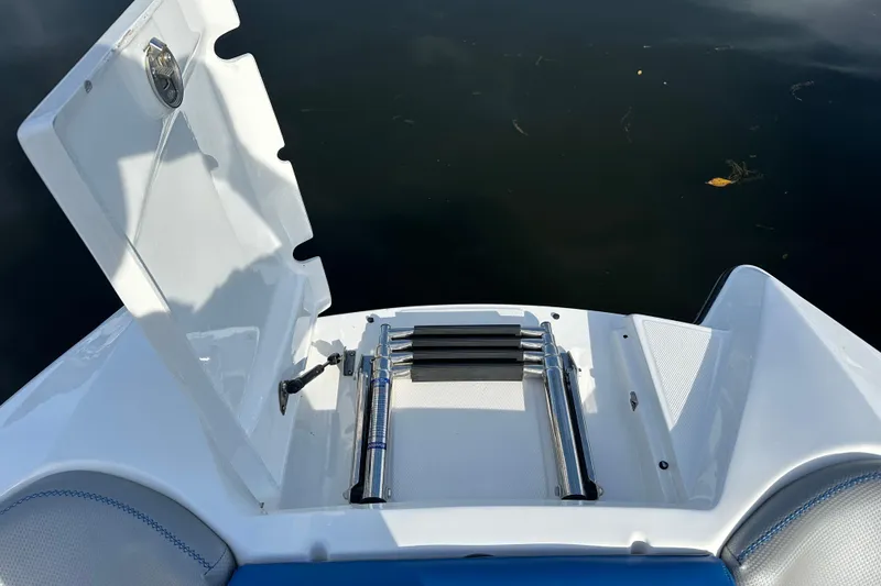Slide: The Image of 2016 MasterCraft X23 boat with open swim platform ladder, docked on calm water. - 21
