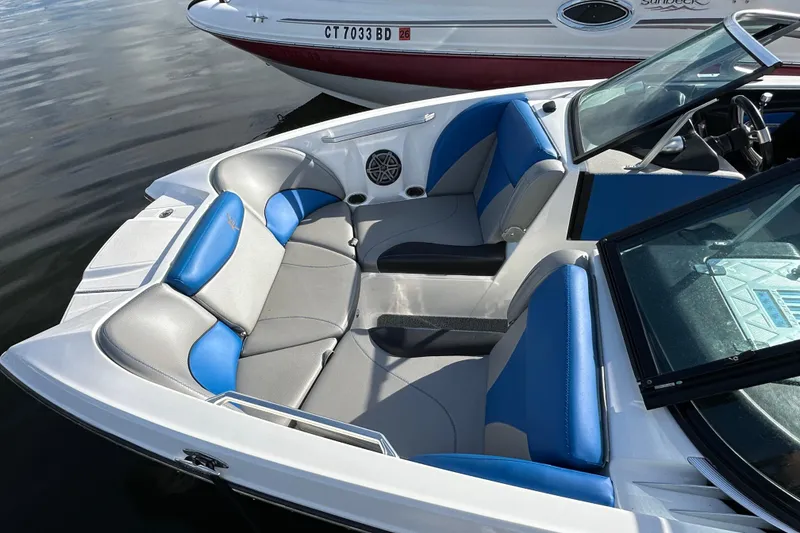 Slide: The Image of 2016 MasterCraft X23 boat interior with blue and gray seating, docked on calm water. - 24