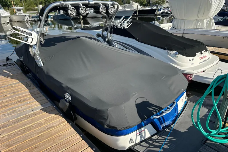 Slide: The Image of 2016 MasterCraft X23 boat covered at a dock, surrounded by other boats. - 27