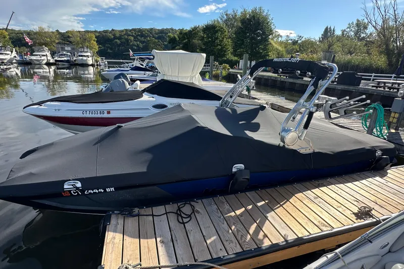 Slide: The Image of 2016 MasterCraft X23 boat covered at a marina dock, surrounded by other boats. - 28