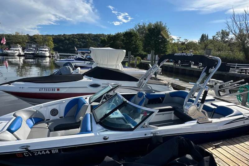 Slide: The Image of 2016 MasterCraft X23 boat docked at a marina with other boats in the background. - 29