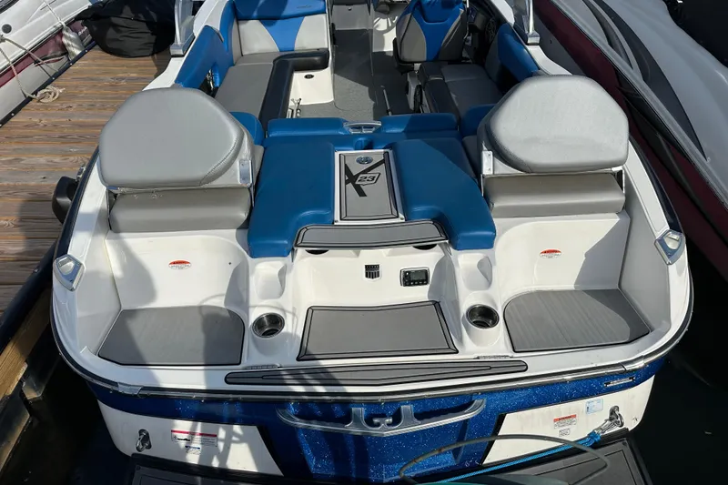 Slide: The Image of 2016 MasterCraft X23 boat interior with blue and gray seating, docked at a marina. - 3