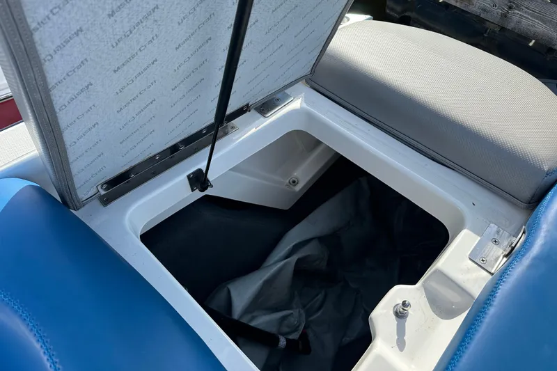 Slide: The Image of Open storage compartment in 2016 MasterCraft X23 boat with blue and gray seating. - 6