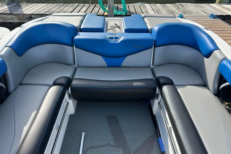 Slide: The Image of 2016 MasterCraft X23 boat interior with blue and gray seating, docked at a marina. - 7
