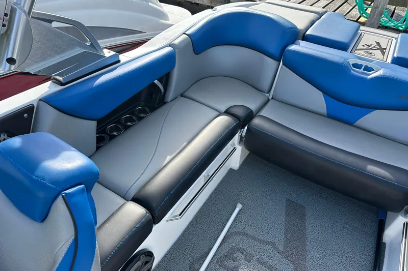 Slide: The Image of 2016 MasterCraft X23 boat interior with blue and gray seating, cup holders, and sleek design. - 8
