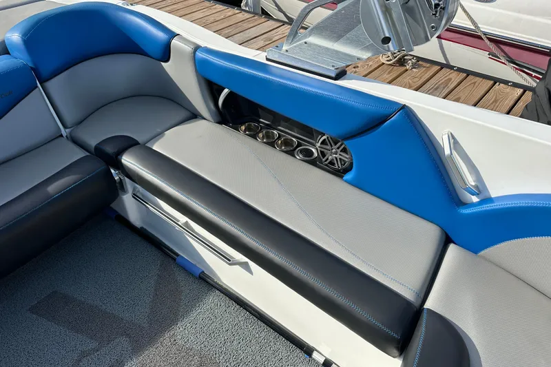 Slide: The Image of 2016 MasterCraft X23 boat interior with blue and gray seating, cup holders, and speaker. - 9