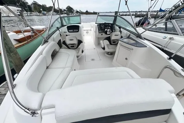Slide: The Image of 2011 Chaparral 224 Sunesta boat interior with white seating, docked by the water. - 11