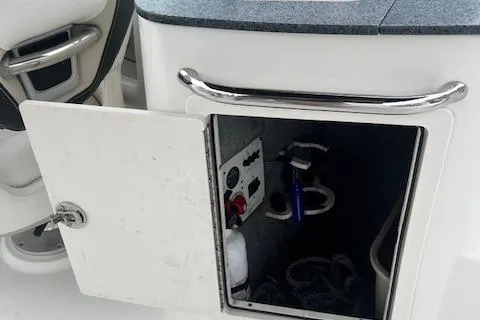Slide: The Image of Open storage compartment on 2011 Chaparral 224 Sunesta boat, showing interior equipment and controls. - 13