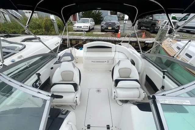 Slide: The Image of 2011 Chaparral 224 Sunesta boat interior with seating and canopy, docked near vehicles. - 15