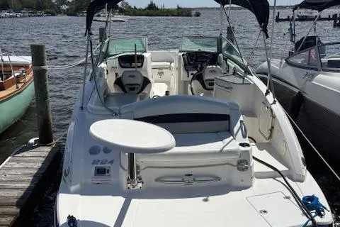 Slide: The Image of 2011 Chaparral 224 Sunesta boat docked, featuring spacious seating and dual consoles. - 2