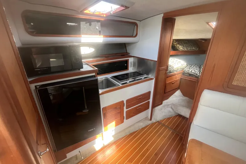 Slide: The Image of 1987 Tiara Yachts 3100 Open interior with kitchen, microwave, and cozy sleeping area. - 11