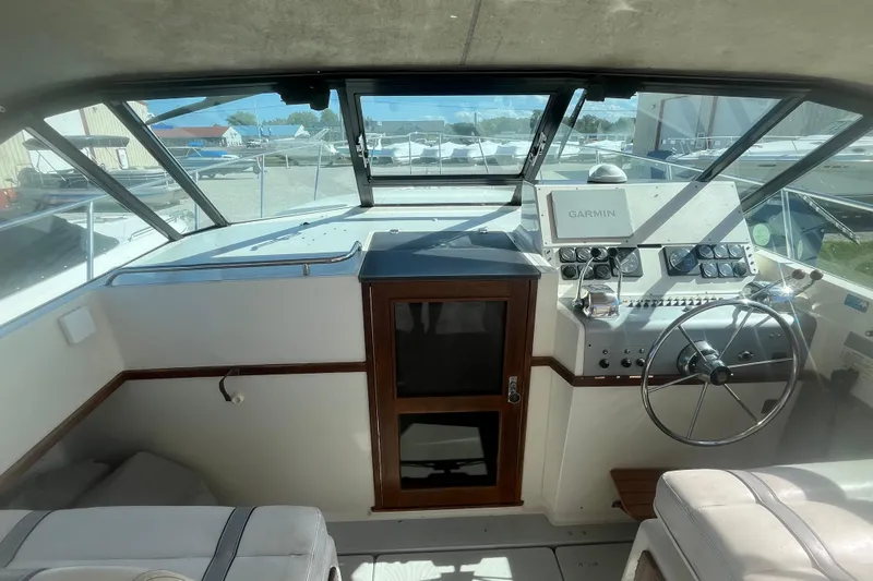 Slide: The Image of 1987 Tiara Yachts 3100 Open helm with Garmin navigation, steering wheel, and control panel. - 7