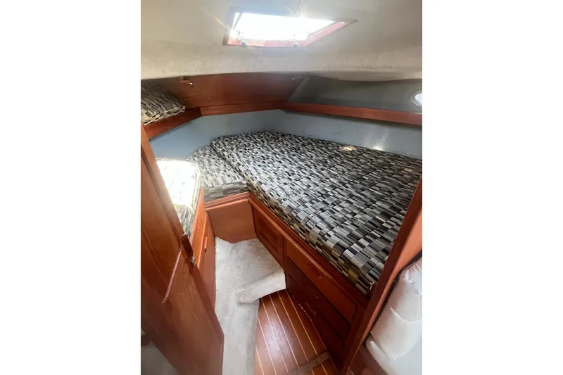 Slide: The Image of 1987 Tiara Yachts 3100 Open cabin interior with patterned bedding and wooden accents. - 9