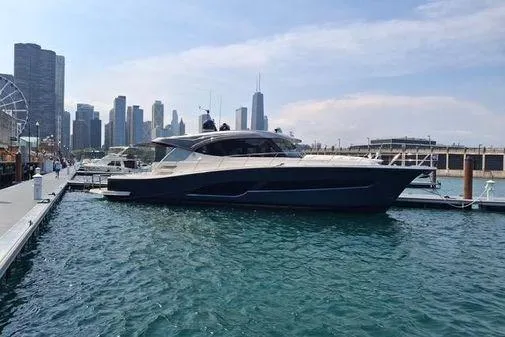 Slide: The Image of 2025 Riviera 585 SUV yacht docked in urban marina with city skyline backdrop. - 1