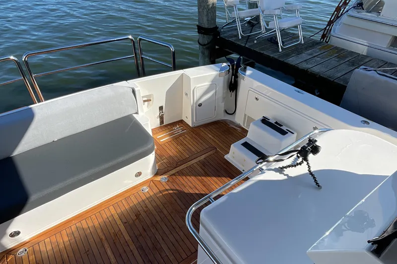 Slide: The Image of 2025 Riviera 585 SUV yacht deck with seating and wooden flooring by the water. - 10