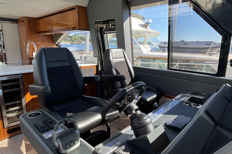 Slide: The Image of 2025 Riviera 585 SUV helm with luxurious seating and modern controls, overlooking marina. - 43