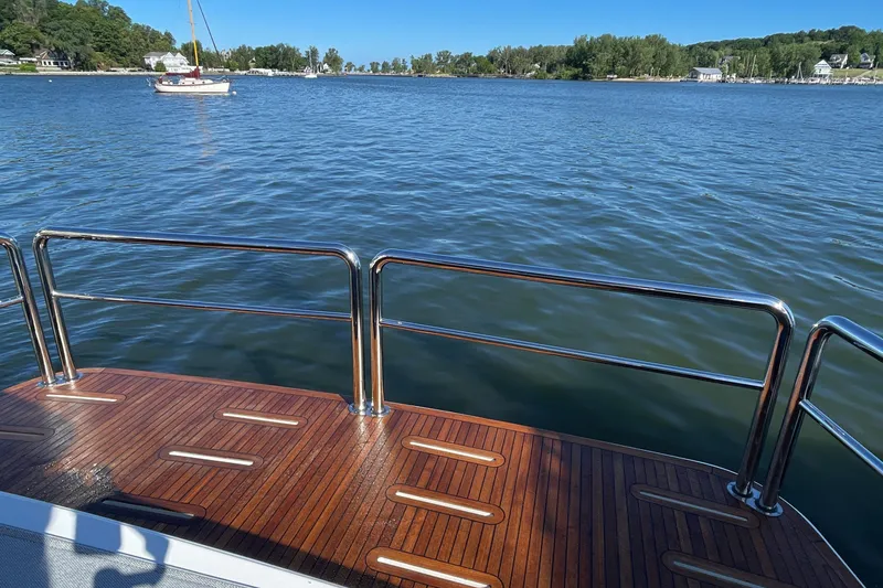 Slide: The Image of Deck view from 2025 Riviera 585 SUV yacht overlooking serene lake and distant sailboat. - 5