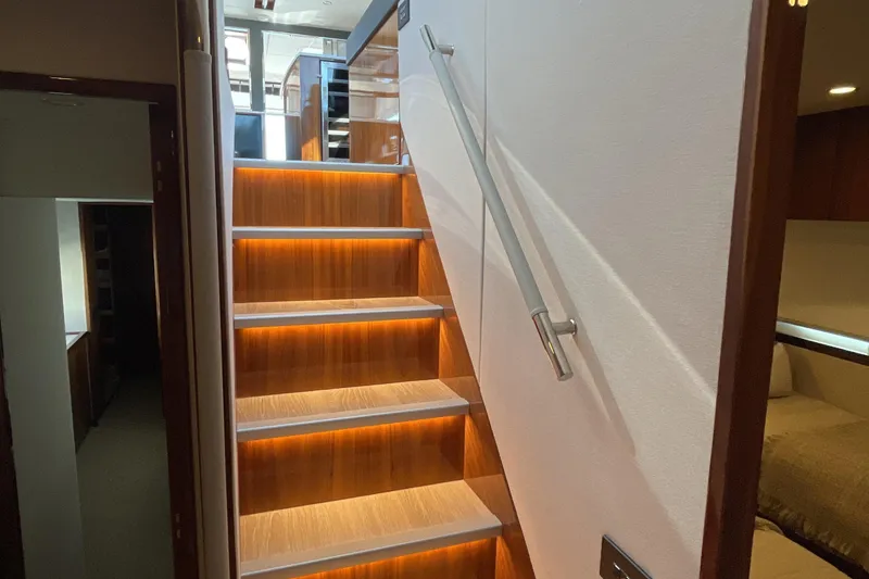Slide: The Image of Interior of 2025 Riviera 585 SUV yacht with illuminated wooden staircase. - 50