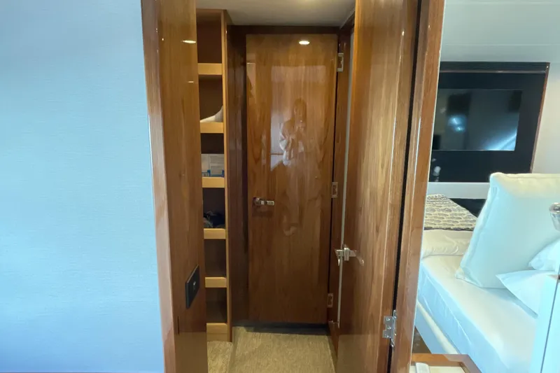 Slide: The Image of Interior of 2025 Riviera 585 SUV yacht with wooden cabinetry and cozy bedroom. - 58