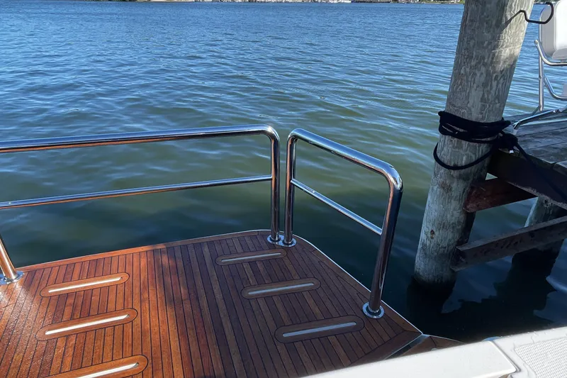Slide: The Image of Riviera 585 SUV 2025 yacht deck with railing, docked by calm waters. - 6