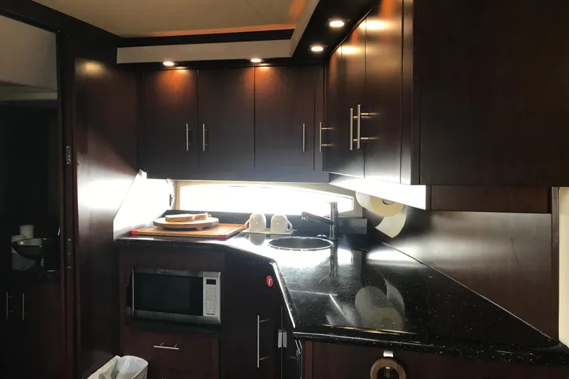 Slide: The Image of Luxurious kitchen interior of 2013 Regal 42 Sport Coupe yacht with dark wood cabinets. - 28