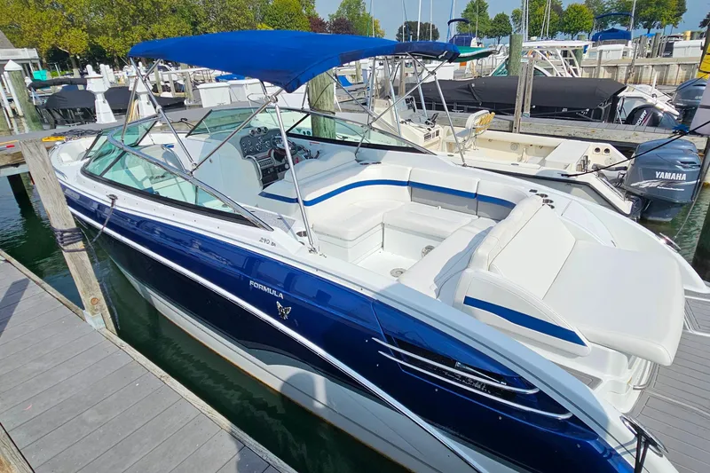 Slide: The Image of 2011 Formula 290 Bowrider boat docked, featuring blue and white design with canopy. - 8