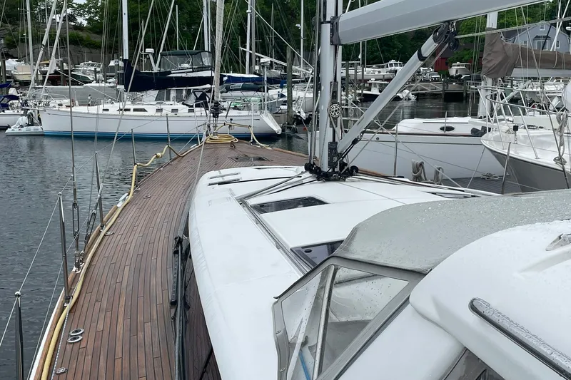 Slide: The Image of 2017 Beneteau Sense 57 sailboat docked in a marina, showcasing sleek design and wooden deck. - 102
