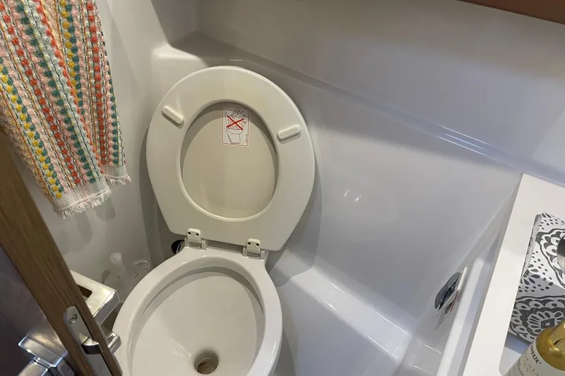 Slide: The Image of Bathroom interior of 2017 Beneteau Sense 57 yacht, featuring a toilet and colorful towel. - 106